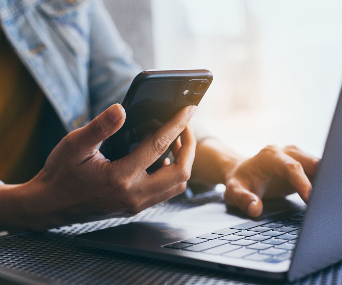 An individual is using a smartphone, with their hands visible on the screen and keyboard of the device.